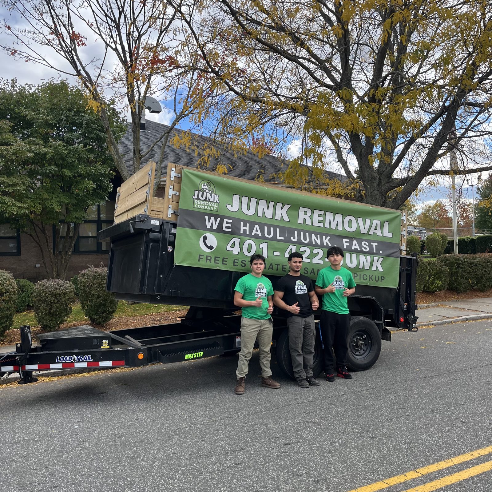 The That Junk Removal Company crew standing in front of their branded dump trailer